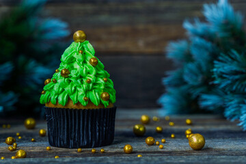 Christmas tree made of cupcake, cream decorated with gold balls. New Year card. Christmas in a rustic style. Copy space. Minimalism. Blurred background.