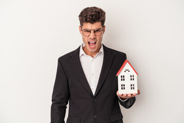 Young real estate caucasian agent isolated on white background screaming very angry and aggressive.