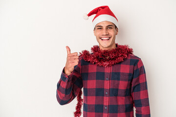 Young caucasian man celebrating Christmas isolated on white background smiling and raising thumb up