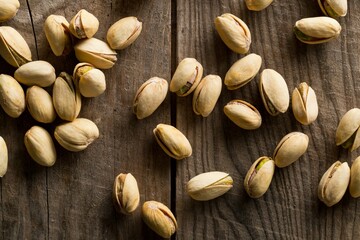 Heap of salted, roasted green pistachio nuts snack on wood background, healthy food snack
