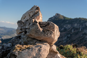 Close-up with stacked stones and a mountainous landscape behind.