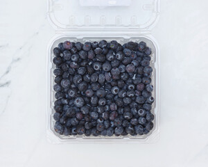 Close-up view of a clear transparent plastic container with fresh blueberries