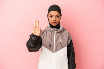 Young Arab woman with sport burqa isolated on pink background standing with outstretched hand...