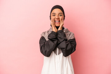 Young Arab woman with sport burqa isolated on pink background shouting excited to front.