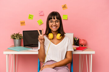 Young mixed race woman preparing a exam in the room listening to music isolated on pink background showing number two with fingers.