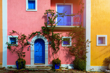 Traditional street with greek houses with flowers in Assos, Kefalonia island. Traditional colorful greek houses in Assos village. Blooming fuchsia plant flowers. Kefalonia island, Greece
