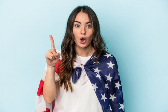 Young caucasian woman holding an American flag isolated on blue background having some great idea, concept of creativity.