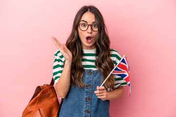 Young caucasian student woman studying English isolated on pink background surprised and shocked.