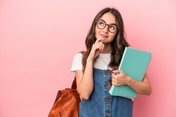 Young caucasian student woman isolated on pink background looking sideways with doubtful and...