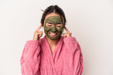 Young caucasian woman wearing a facial mask isolated on white background covering ears with hands.