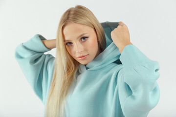 Young pretty woman wearing turquoise hoodie on white background
