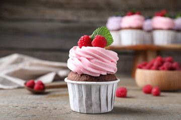 Sweet cupcake with fresh raspberries on wooden table