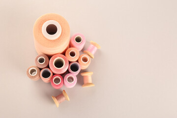 Different shades of pink sewing threads on light background, flat lay. Space for text