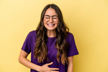 Young caucasian woman isolated on yellow background touches tummy, smiles gently, eating and satisfaction concept.