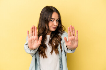 Young caucasian woman isolated on yellow background standing with outstretched hand showing stop...