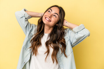 Young caucasian woman isolated on yellow background feeling confident, with hands behind the head.