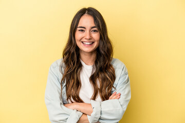 Young caucasian woman isolated on yellow background who feels confident, crossing arms with determination.