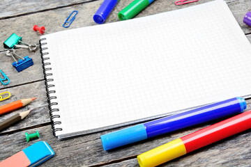 School supplies with empty notebook on wooden desk