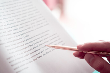A person reading research paper with a pencil as a visual pacer to improve reading speed