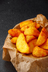 wedges potato in bowl closeup. wedges potato on dark concrete table