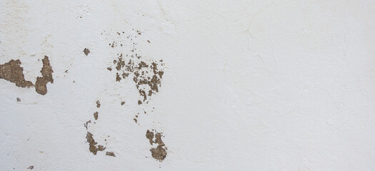 Old cracked weathered shabby white painted plastered peeled wall background. Chipped broken uneven rough stucco wall texture wallpaper