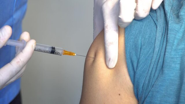 Nurse or medical staff in white gloves putting the vaccine with a needle in the arm to a boy for Covid-19 or coronavirus Sars Cov to avoid becoming seriously ill and the rise of the pandemic.
