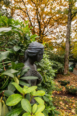 schöne Frauenbüste inmitten einer Kirschlorbeerhecke