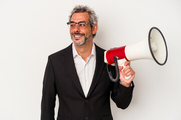 Middle age business man holding a megaphone isolated on white background  looks aside smiling, cheerful and pleasant.