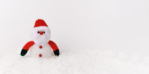 Santa Claus doll toy on christmas time, background with snow. Front view. Banner. Copy space.