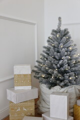 Elegant Christmas tree with white toys and gift boxes in the bedroom of luxury apartments