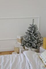 Elegant Christmas tree with white toys and gift boxes in the bedroom of luxury apartments