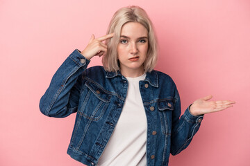 Young caucasian woman isolated on pink background showing a disappointment gesture with forefinger.