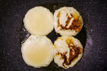 The detail of four cheeses on the non-stick frying pan made of eartenware. 