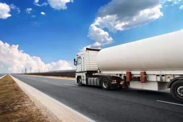 Tanker truck on a countryside road against a sky with clouds - 465107336