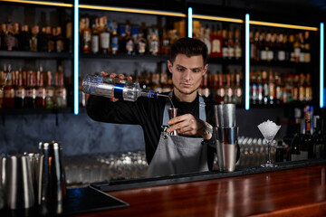 Bartender in apron adds ingredient to shaker