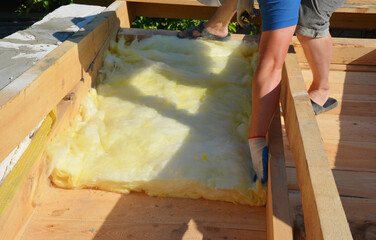 House Roof Insulation. A roofer is installing mineral wool insulation between the roof rafters and loft joists. Roofing construction.