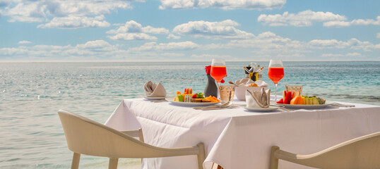 Luxury breakfast table with food for two with beautiful tropical sea view background. Morning couple time summer holiday and romantic vacation concept, luxury travel and lifestyle, destination dining