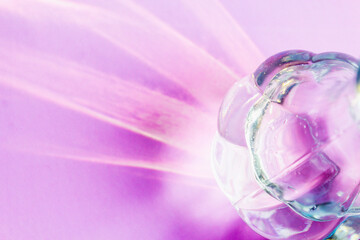 A glass vase on a light lilac background with hard shadows and sun glare. Reflection of light from glass. Abstract background