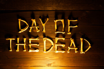 Lettering from the bones of the words Day of the Dead on a beautiful dark brown wooden background. Design to celebrate Dia de los Muertos. Scary inscription. Copy space for text. Close-up