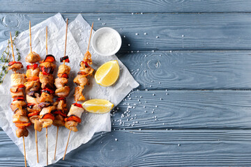 Grilled chicken skewers with vegetables on color wooden background