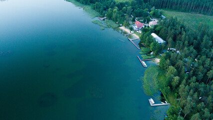Naklejka na ściany i meble Aerial view of the lake and docked boats in a daylight. Bird's eye view of the green forest. 