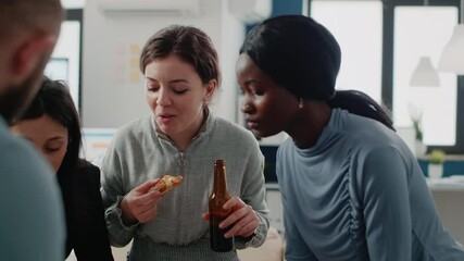 Group of colleagues having fun with drinks after work. Workmates enjoying bottles of beer and pizza while playing at foosball game table for entertainment. Coworkers after hours