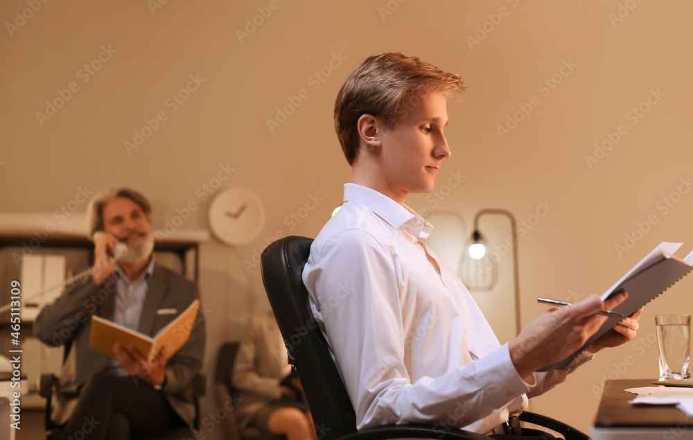 Wall mural Young businessman working with documents in office at night