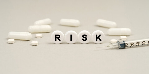 On the table are capsules, a syringe and pills that say - RISK