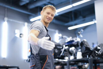 Fototapeta na wymiar Smiling young car mechanic stands in workshop closeup