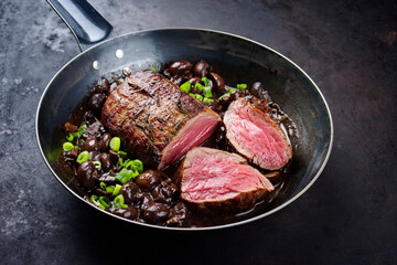 Traditional fried dry aged angus beef filet roast and medaillon natural with mushrooms in red wine sauce served as close-up in classic skillet