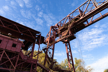 Overhead industrial metal structures with stairs and catwalks, blue sky beyond, horizontal aspect