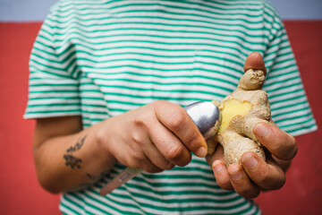 hands of a woman peeling ginger with a spoon