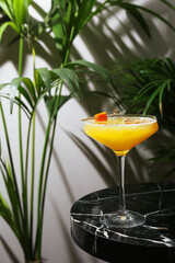 summer cocktail with citrus on marble table and tropic plants on back. cocktail witg citrus.