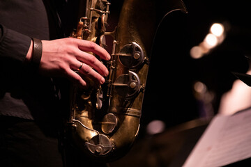A tenor saxophone player playing a solo in front of a microphone during a live concert